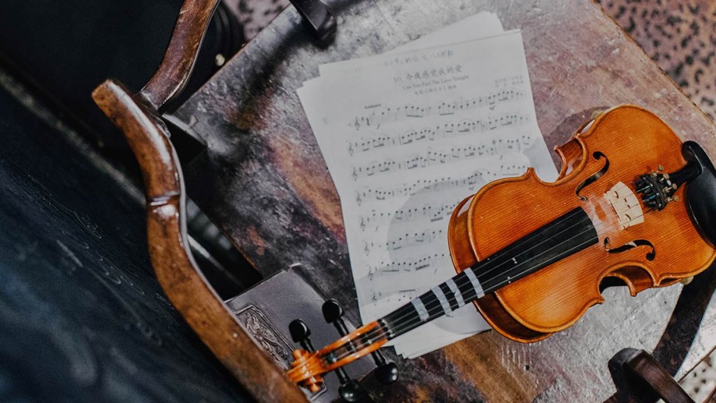 Violine und Notenblätter auf altem Holzstuhl