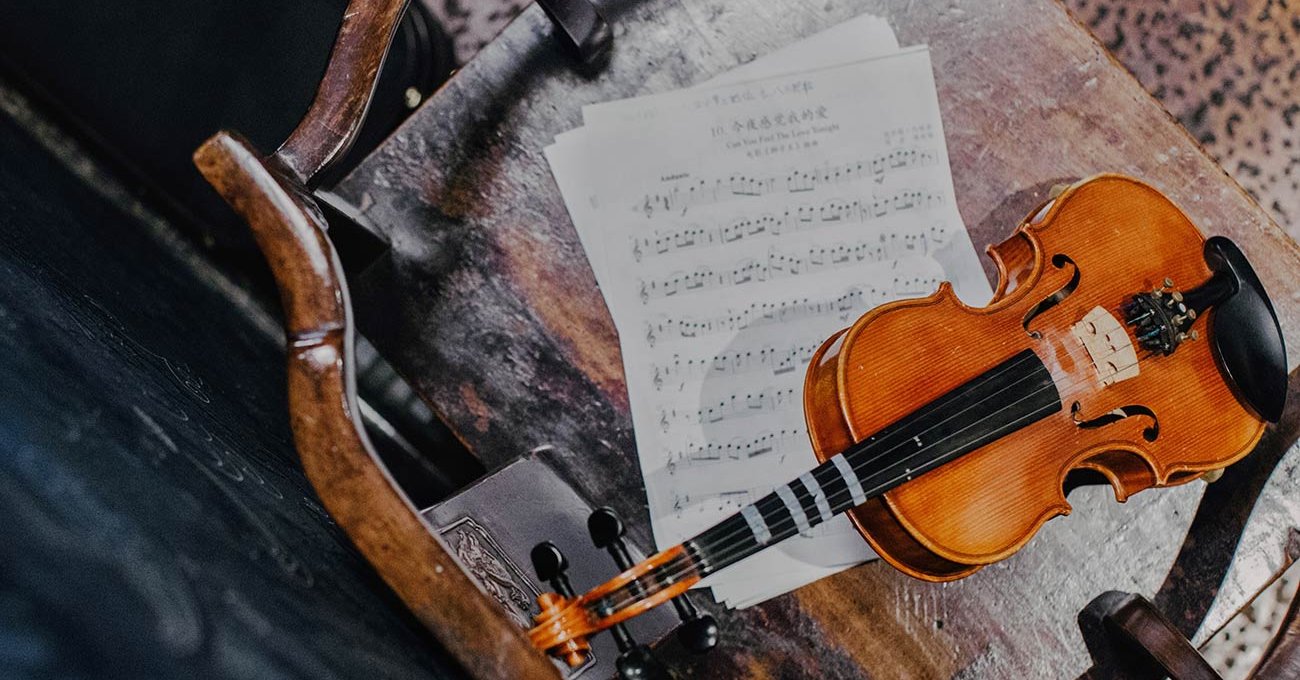 Violine und Notenblätter auf altem Holzstuhl