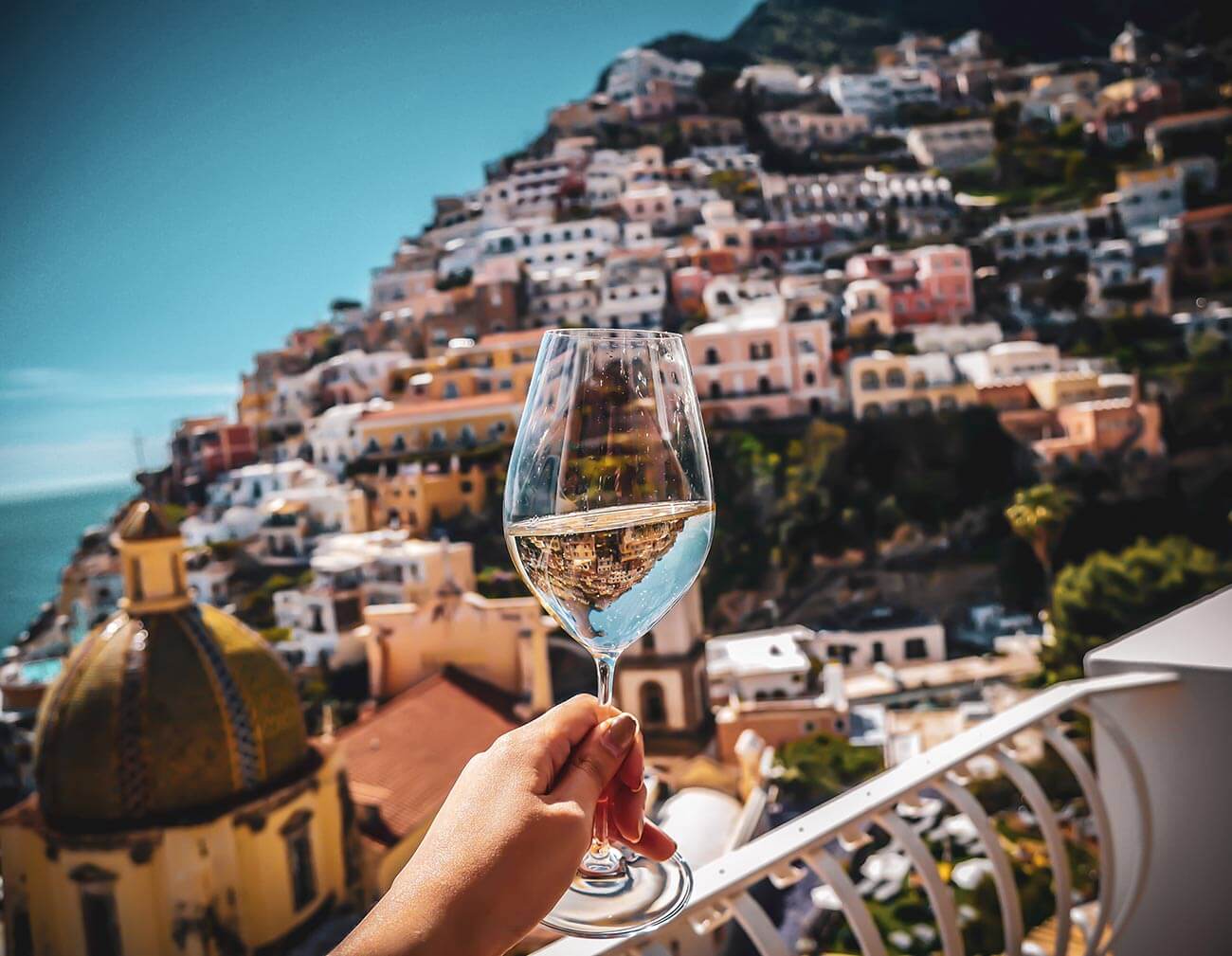 Donna che tiene in mano un bicchiere di vino con parete bianca sullo sfondo di Positano