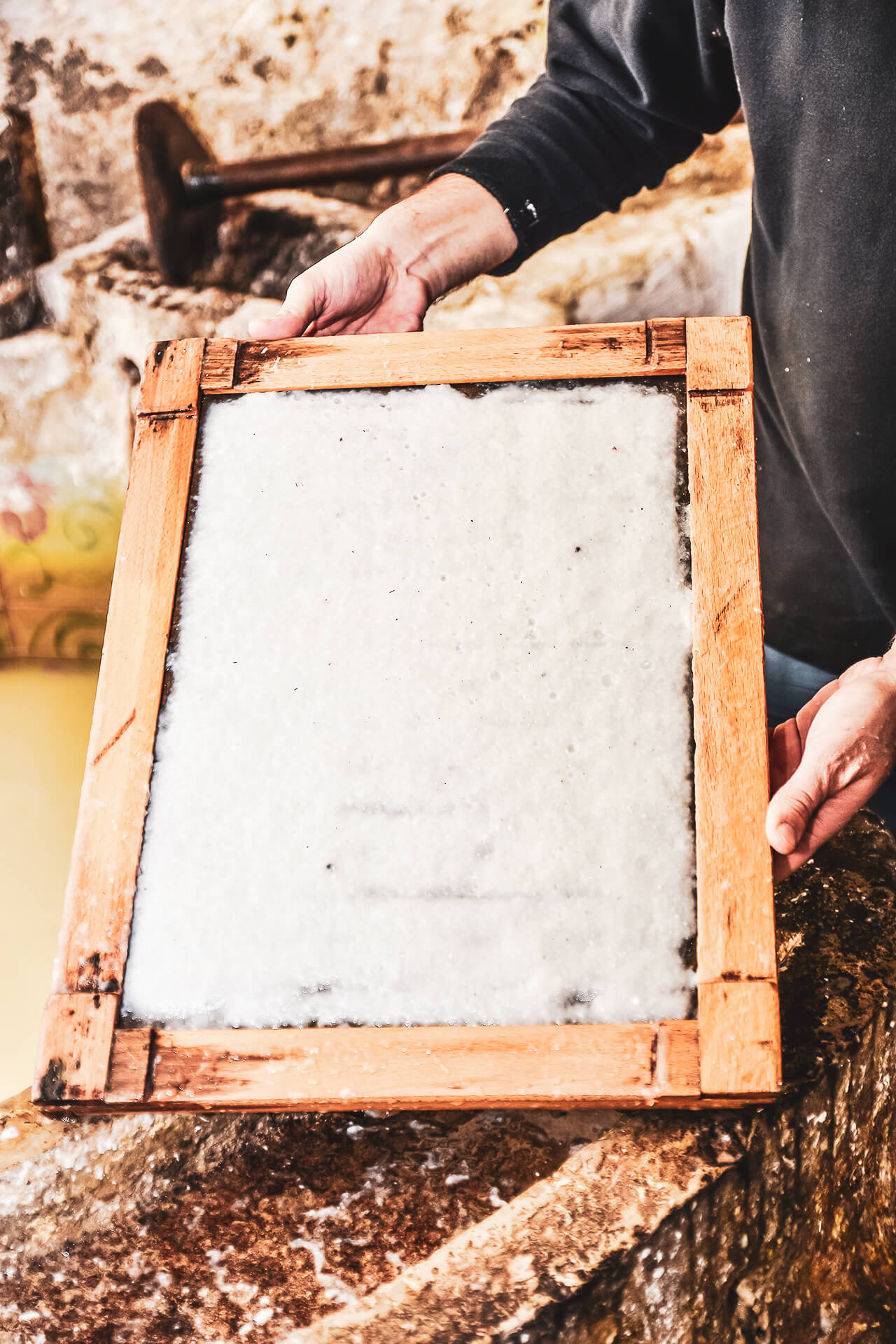 La pasta di carta su un telaio di legno viene tenuta in vista della fotocamera.