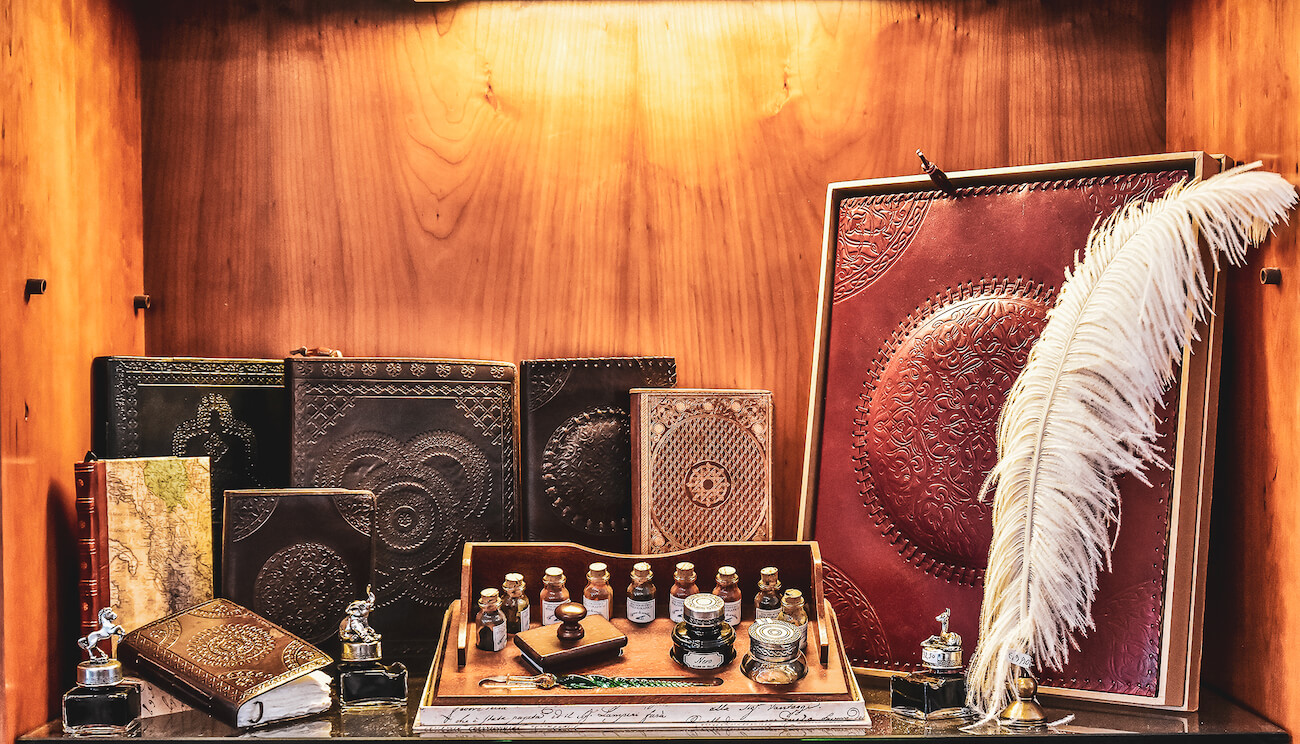 Leather books and inkwells on a wooden shelf